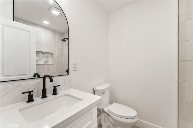 bathroom with tasteful backsplash, vanity, baseboards, and toilet