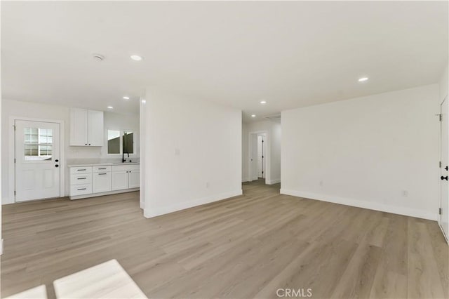 unfurnished living room with recessed lighting, light wood-style flooring, and baseboards