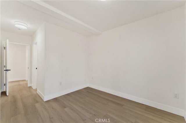 spare room with baseboards and light wood-type flooring