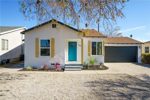 view of front of property with concrete driveway, an attached garage, a shingled roof, and stucco siding
