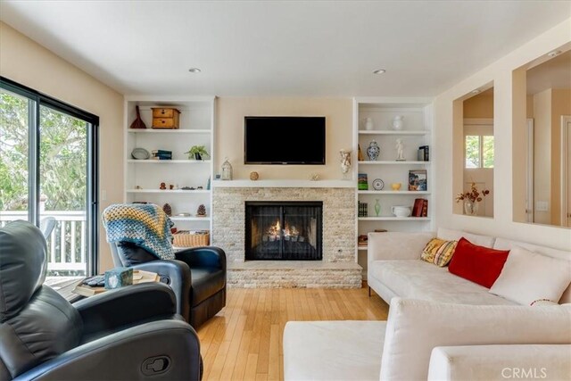 2180 Benson Ave, Cambria, CA 93428 - living area with wood-type flooring, built in shelves, and a warm lit fireplace