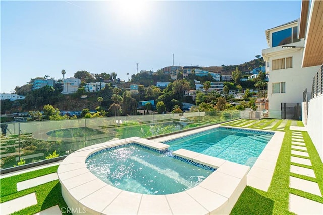 pool featuring an in ground hot tub and fence