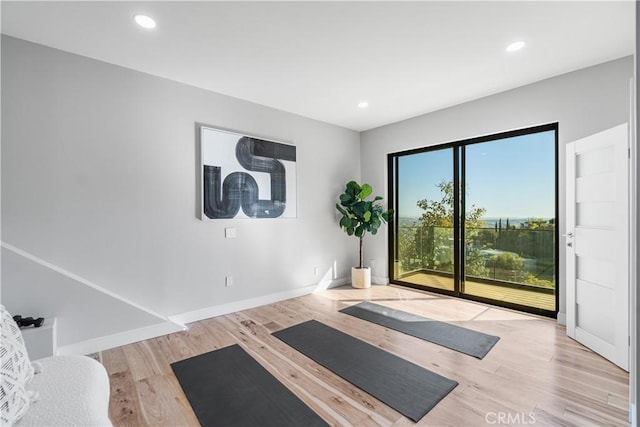 exercise area featuring baseboards, recessed lighting, and wood finished floors