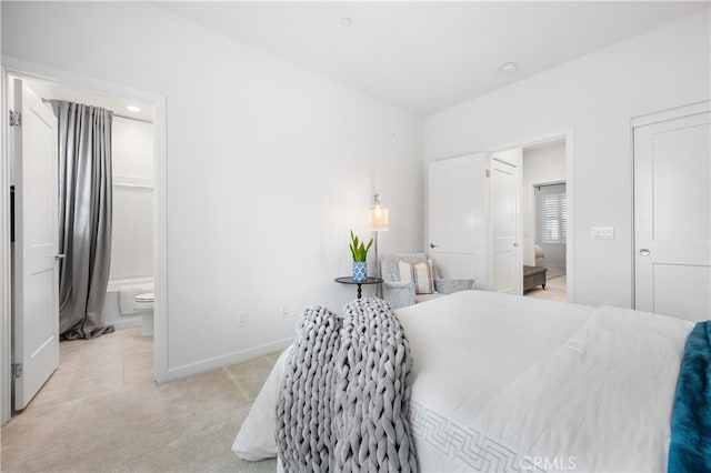 bedroom featuring ensuite bath, baseboards, light tile patterned flooring, and light carpet