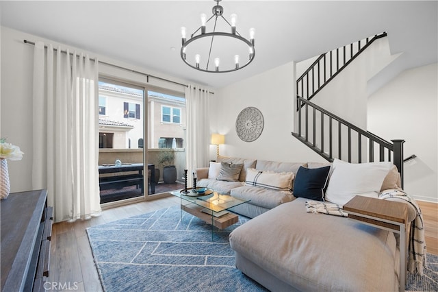 living room featuring stairway, wood finished floors, and an inviting chandelier