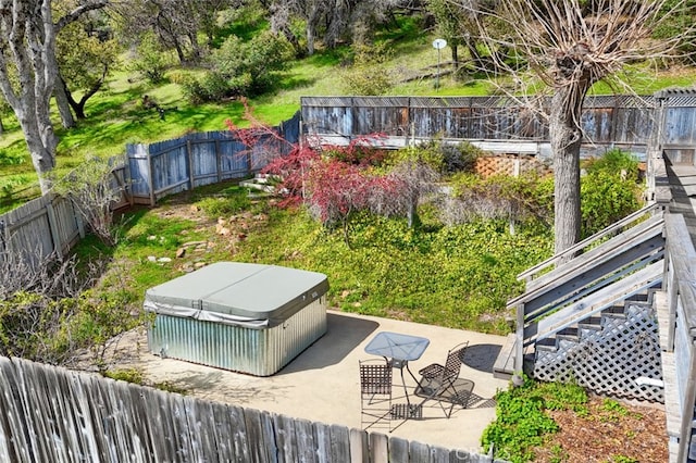 view of yard featuring a patio area, a fenced backyard, a hot tub, and stairs