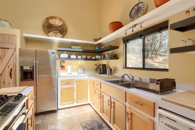 kitchen with light brown cabinetry, open shelves, light countertops, a sink, and appliances with stainless steel finishes
