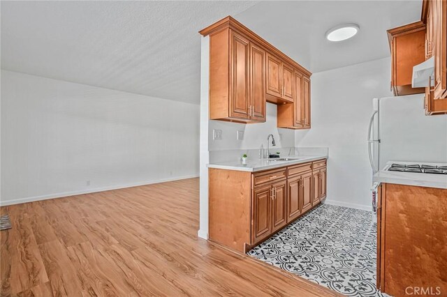 1101 E Ocean Blvd Unit 14, Long Beach, CA 90802 - kitchen with a sink, light countertops, baseboards, light wood-type flooring, and brown cabinetry