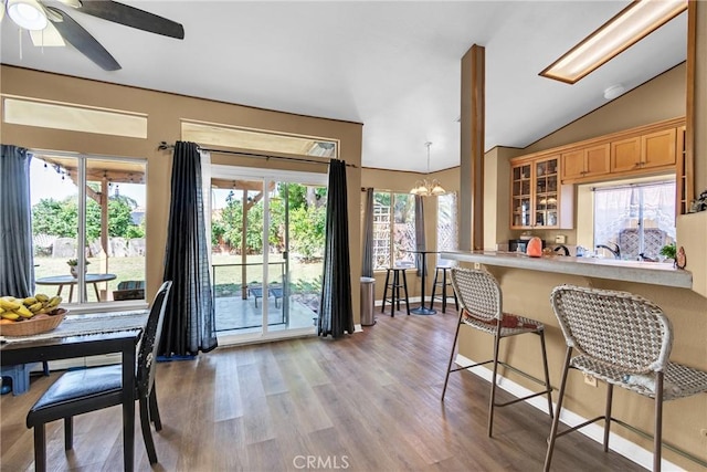25351 Chicago Ave, Hemet, CA 92544 - kitchen featuring glass insert cabinets, a kitchen breakfast bar, light wood-style floors, vaulted ceiling, and ceiling fan with notable chandelier