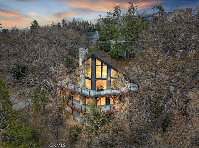 27637 St Bernard Ln, Lake Arrowhead, CA 92352 - property exterior at dusk with a chimney and a balcony