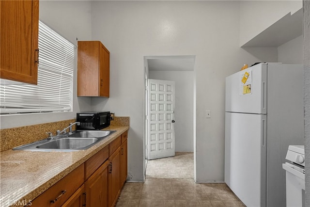 2619 Trinity St, Los Angeles, CA 90011 - kitchen featuring freestanding refrigerator, a sink, brown cabinets, black microwave, and light countertops