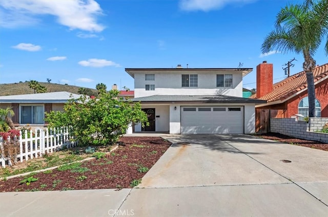 traditional-style home featuring driveway, stucco siding, fence, and a garage