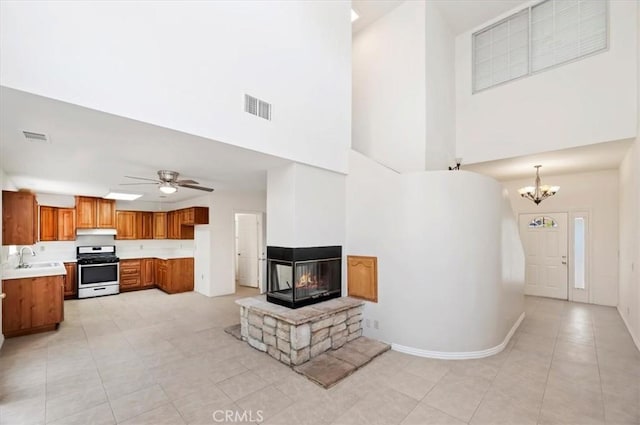 living room with a multi sided fireplace, a high ceiling, light tile patterned floors, and visible vents