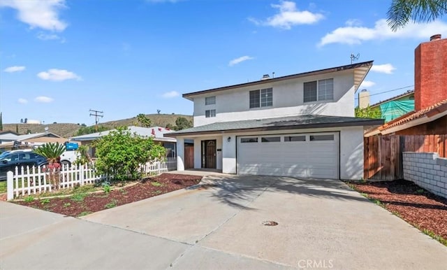 traditional home featuring an attached garage, concrete driveway, stucco siding, and fence
