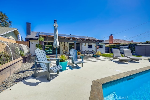 rear view of house with a fenced in pool, a chimney, fence, a patio area, and stucco siding