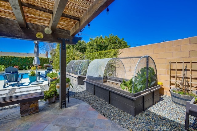 view of patio featuring fence, a fenced in pool, and a vegetable garden