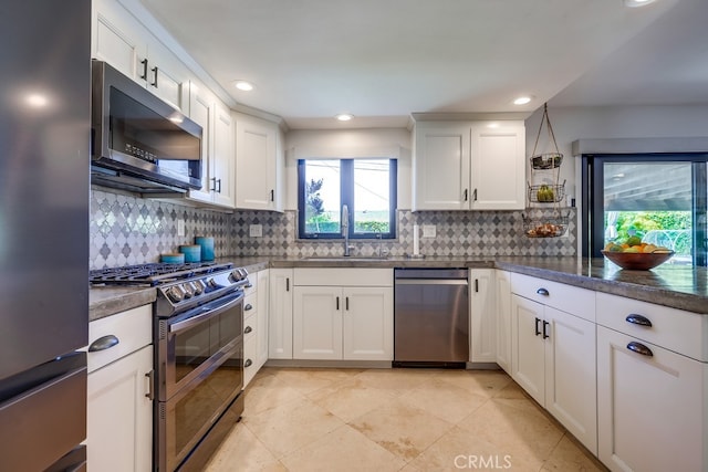 kitchen with white cabinets, stainless steel appliances, a sink, and tasteful backsplash