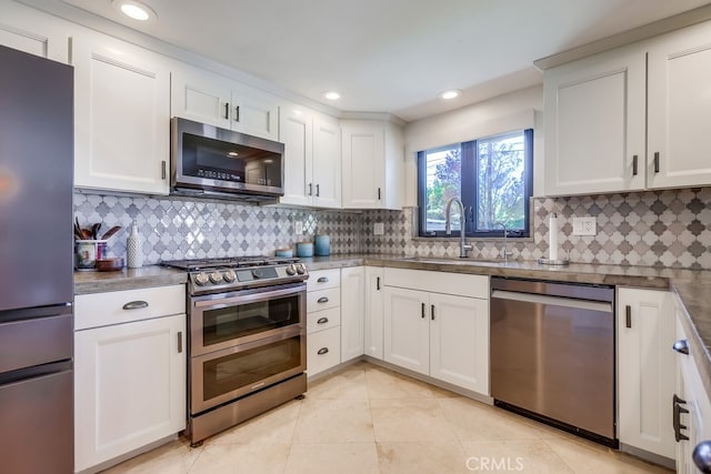 kitchen featuring light tile patterned floors, a sink, appliances with stainless steel finishes, and tasteful backsplash
