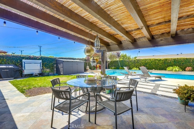 view of patio with a fenced in pool, a fenced backyard, a storage shed, outdoor dining space, and an outbuilding