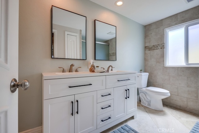 full bathroom featuring double vanity, tile patterned floors, toilet, and a sink