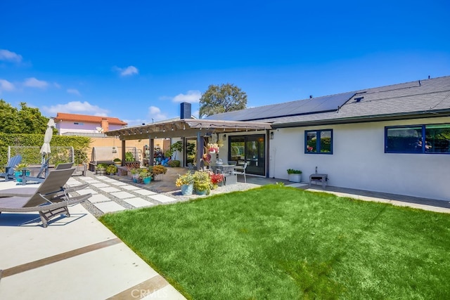 rear view of property with a patio area, a lawn, fence, stucco siding, and solar panels