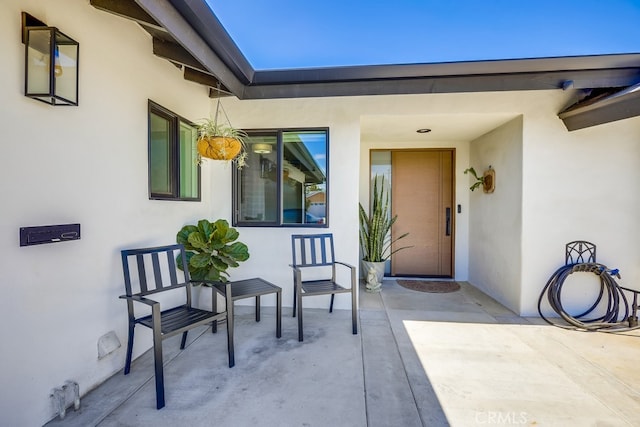 property entrance with stucco siding and a patio area