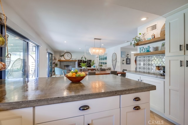kitchen featuring white cabinets, tasteful backsplash, open floor plan, visible vents, and open shelves