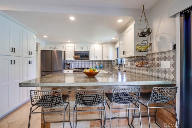 kitchen featuring a peninsula, a sink, white cabinetry, and appliances with stainless steel finishes