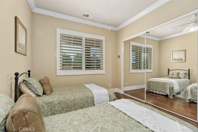 bedroom featuring a closet, baseboards, ornamental molding, visible vents, and wood finished floors