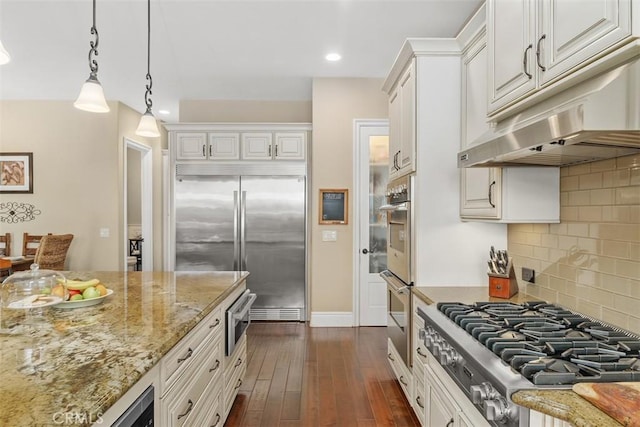 kitchen featuring appliances with stainless steel finishes, under cabinet range hood, white cabinetry, light stone countertops, and dark wood-type flooring