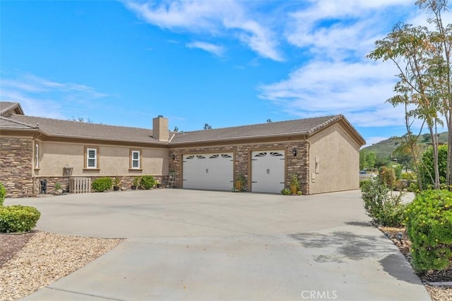 view of home's exterior featuring stone siding, a garage, a chimney, concrete driveway, and stucco siding