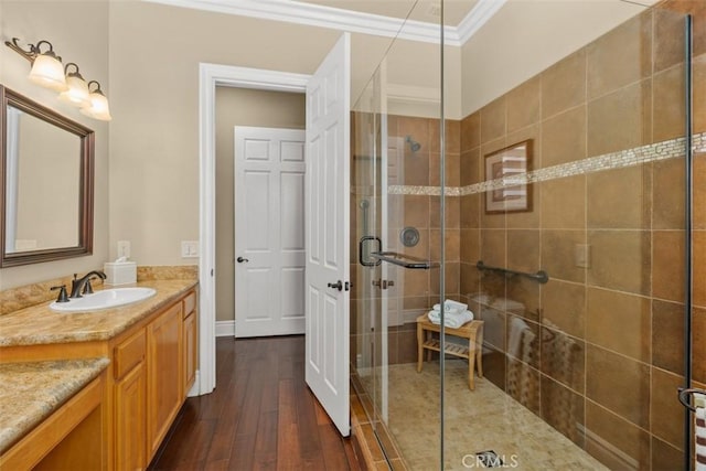 full bath featuring a stall shower, vanity, wood-type flooring, and ornamental molding