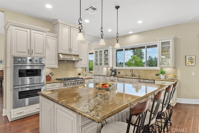 kitchen with dark wood-style flooring, visible vents, appliances with stainless steel finishes, and under cabinet range hood