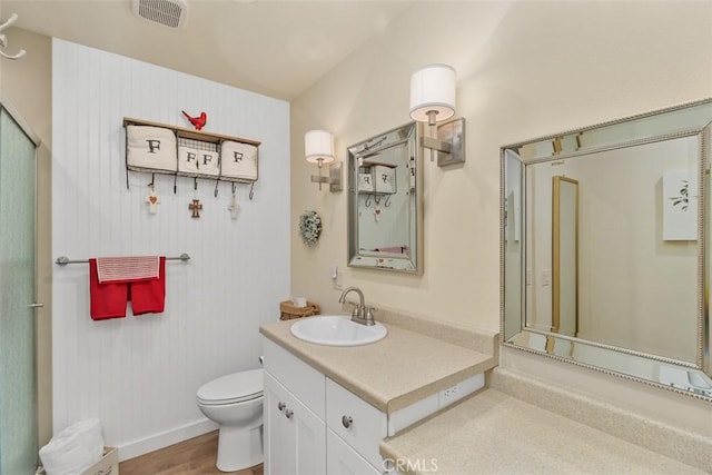 bathroom with vanity, visible vents, toilet, wood finished floors, and baseboards