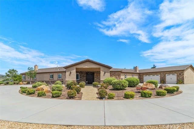 ranch-style home with curved driveway, stucco siding, stone siding, an attached garage, and a chimney