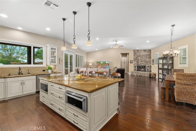 kitchen with visible vents, a sink, dark wood-type flooring, pendant lighting, and open floor plan