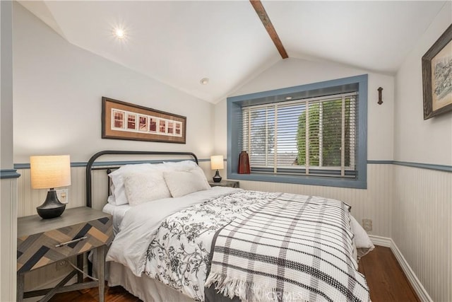 bedroom featuring lofted ceiling with beams, baseboards, a wainscoted wall, and wood finished floors