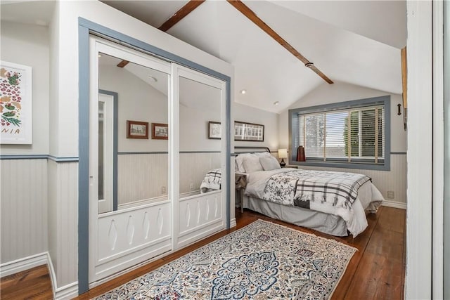 bedroom featuring vaulted ceiling with beams, hardwood / wood-style flooring, and a wainscoted wall