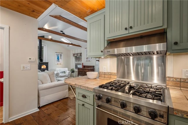 kitchen with a wood stove, green cabinets, tile countertops, and lofted ceiling with beams