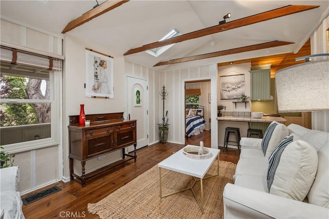 living room featuring wood finished floors, visible vents, a wealth of natural light, and vaulted ceiling with skylight