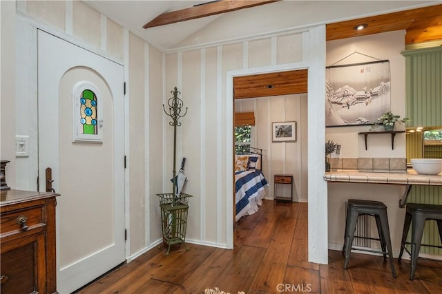 foyer entrance featuring lofted ceiling with beams and dark wood finished floors