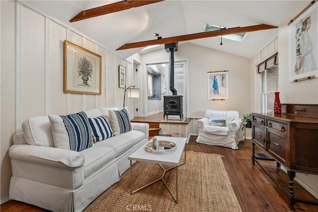 living room featuring dark wood-style flooring, a wood stove, and vaulted ceiling with beams