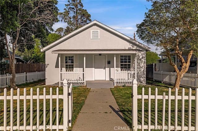 bungalow featuring a porch, a fenced front yard, stucco siding, and a front lawn