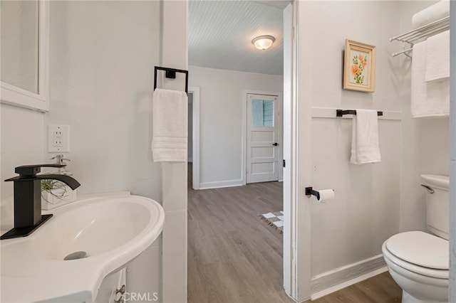 bathroom featuring toilet, wood finished floors, a sink, and baseboards