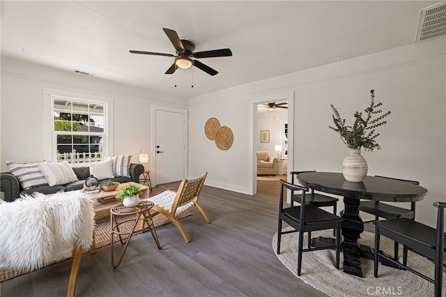 living room featuring dark wood-type flooring, visible vents, and a ceiling fan