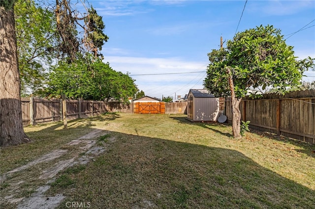 view of yard featuring an outbuilding, a fenced backyard, and a storage unit