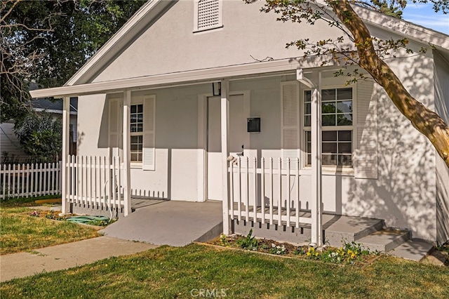 view of front of house with a porch, stucco siding, and fence