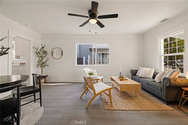 living area with visible vents, baseboards, a ceiling fan, and wood finished floors