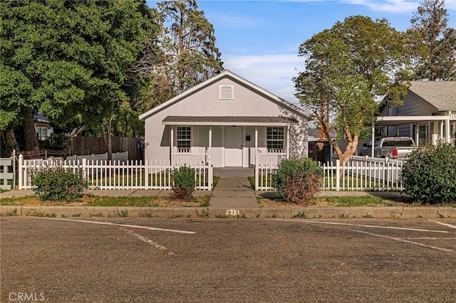 bungalow-style house featuring a fenced front yard and stucco siding