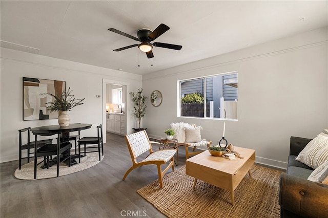 living area featuring wood finished floors, baseboards, and a ceiling fan
